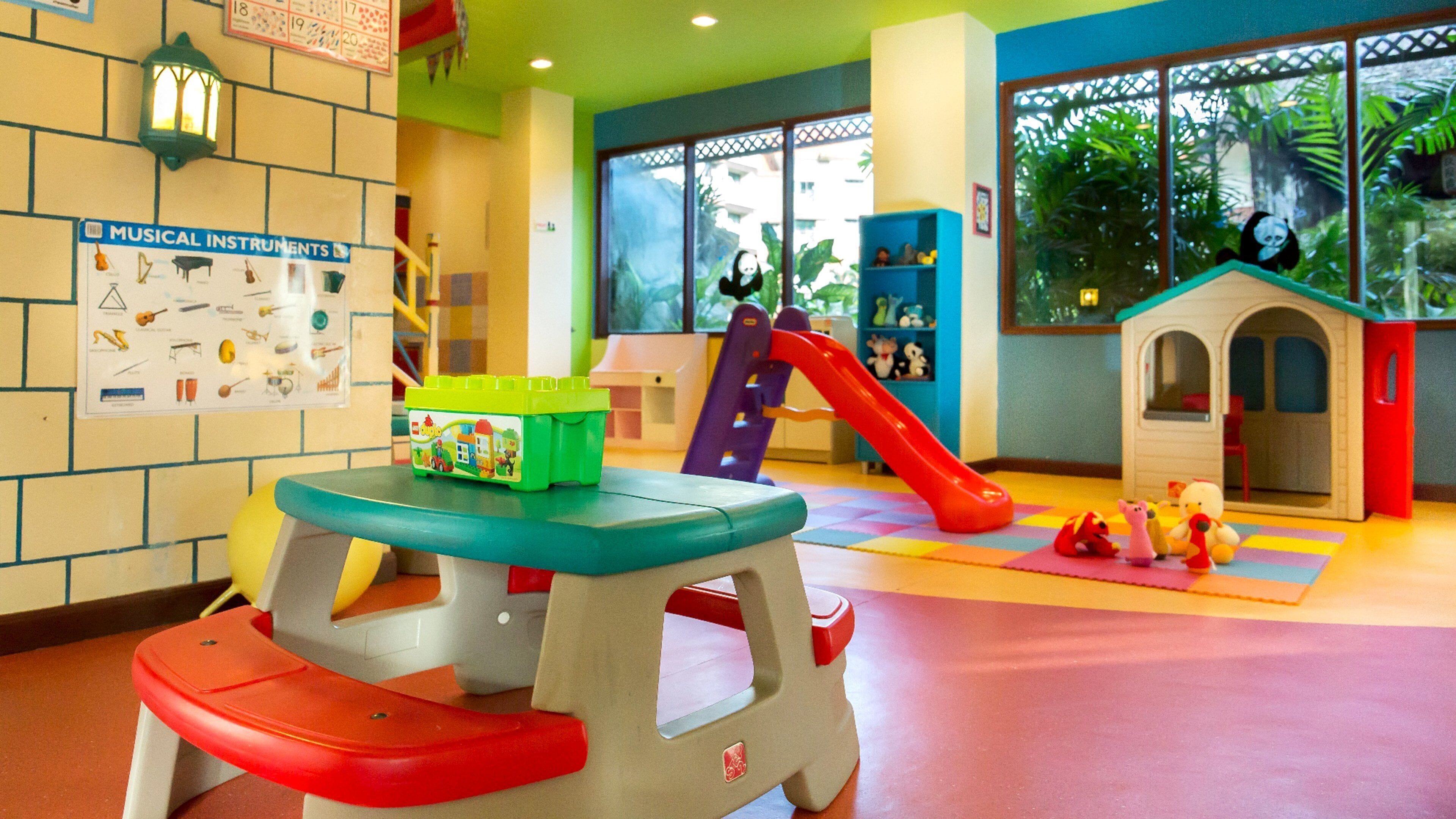 A children's play area with a slide, climbing structures, and a small house.