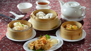 A table with various dishes, including dumplings and fried items, accompanied by bowls of soup and a teapot.