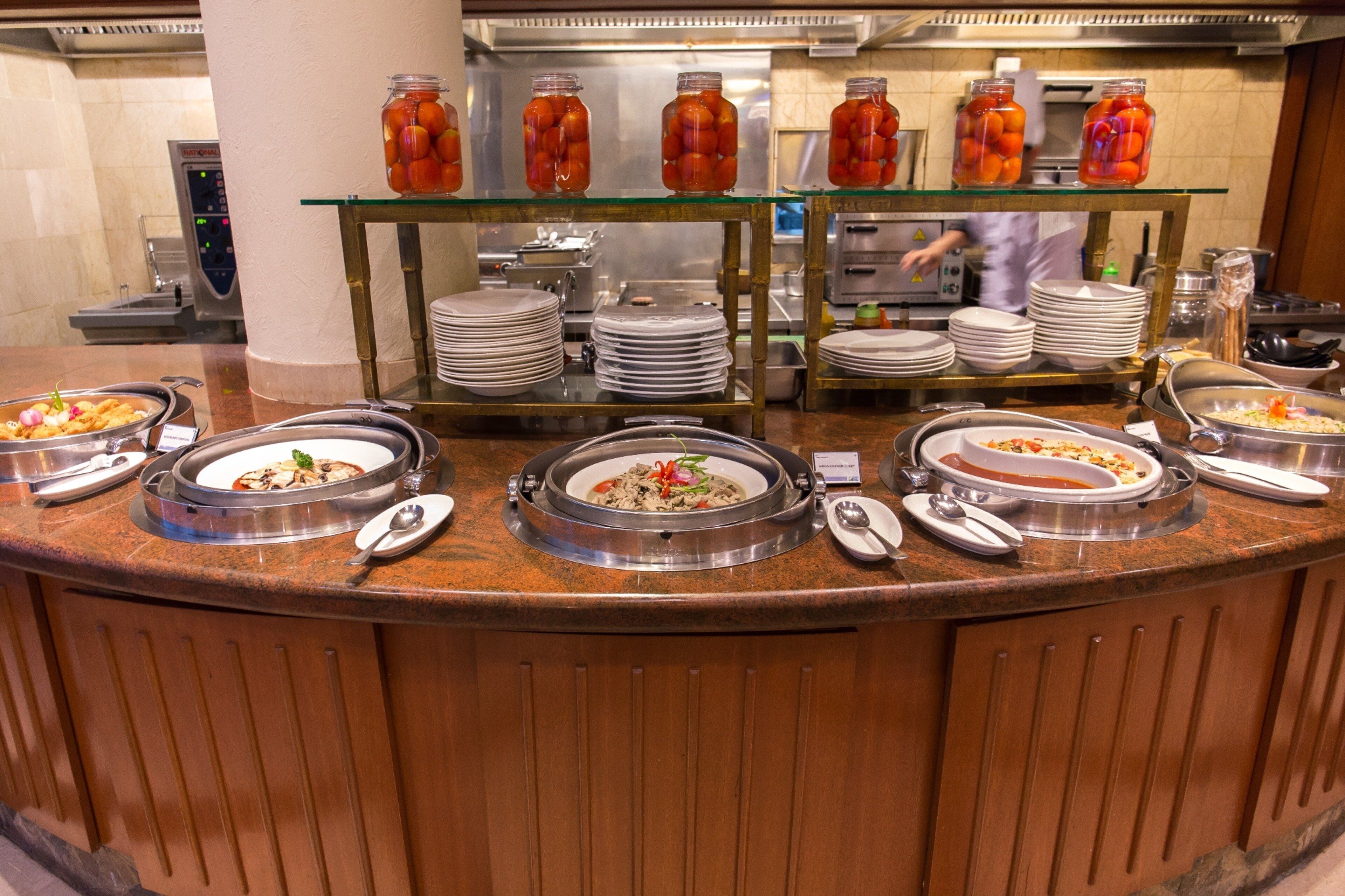 Ein Buffet mit verschiedenen Speisen, Soßen und gestapelten Tellern.