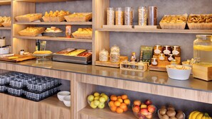 Un bufé con diversas opciones de comida, entre ellas frutas, pasteles y salsas.