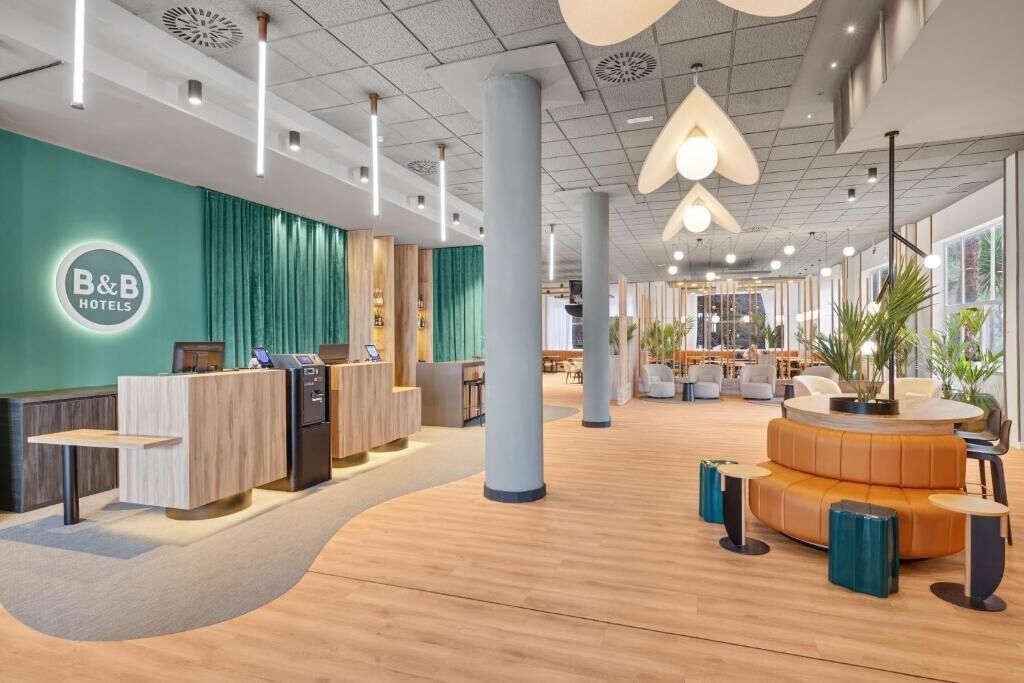 A B&B hotel lobby with a reception desk, seating area, and large windows.