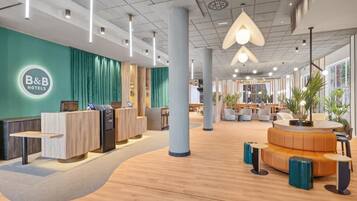 A B&B hotel lobby with a reception desk, seating area, and large windows.