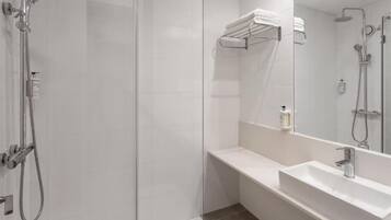 Ein modernes Badezimmer mit Duschkabine aus Glas, einem weißen Waschbecken und einem Handtuchhalter.