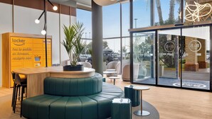 Un moderno vestíbulo de hotel con mostrador de recepción, zona de estar y grandes ventanales.