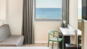 Ein Hotelzimmer mit Bett, Schreibtisch, Stuhl, Fernseher und Meerblick.
