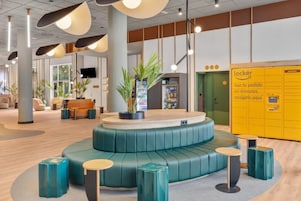 Un hall d’entrée moderne avec un espace salon central, un distributeur automatique et un espace casiers jaune.