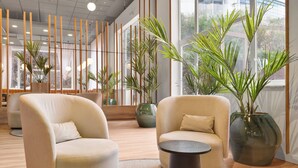 Un interior moderno con dos sillones, una mesita y plantas en macetas.