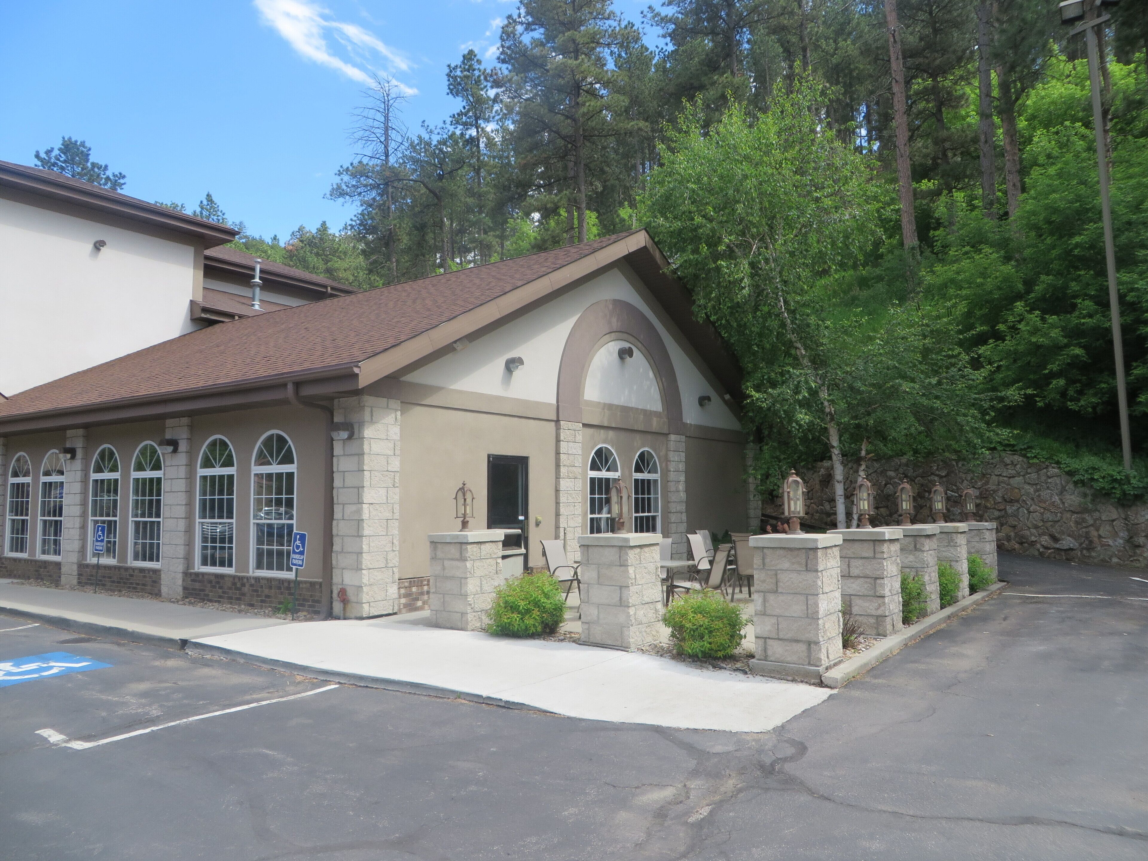 A building with a stone facade, arched windows, and a small porch with chairs.