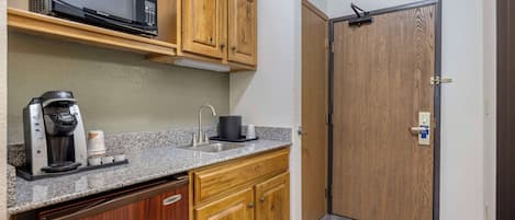 Una cocina compacta con microondas, cafetera y lavamanos.