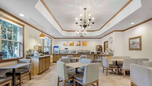 A restaurant with a central dining area, a bar, and a kitchen in the background. - Comfort Inn & Suites Mt. Rushmore (Keystone)