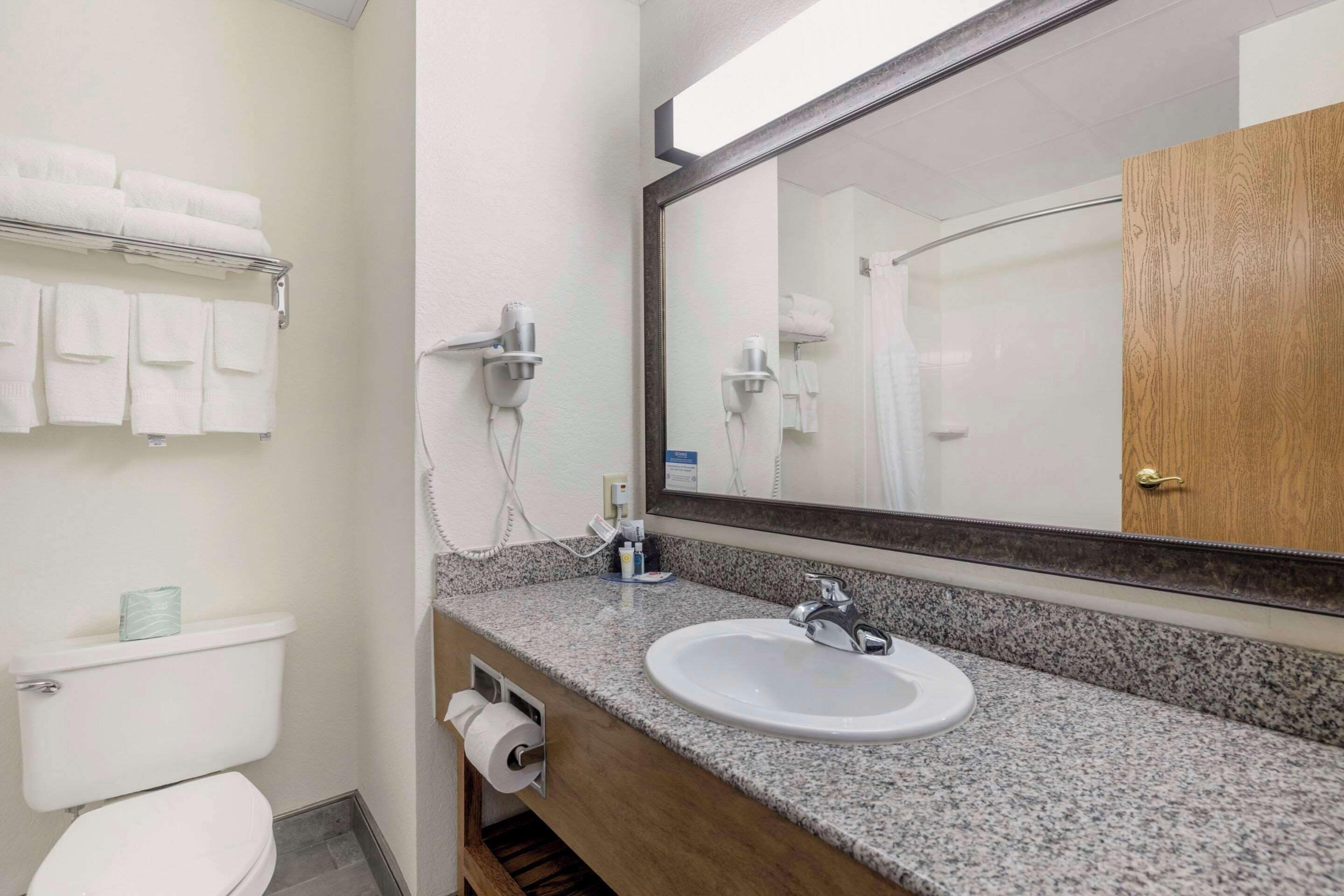 Un baño con un lavamanos blanco, un espejo, un perchero para toallas y un armario de madera.