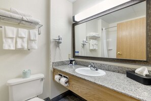 A bathroom with a sink, mirror, towel rack, toilet, and a tissue box.