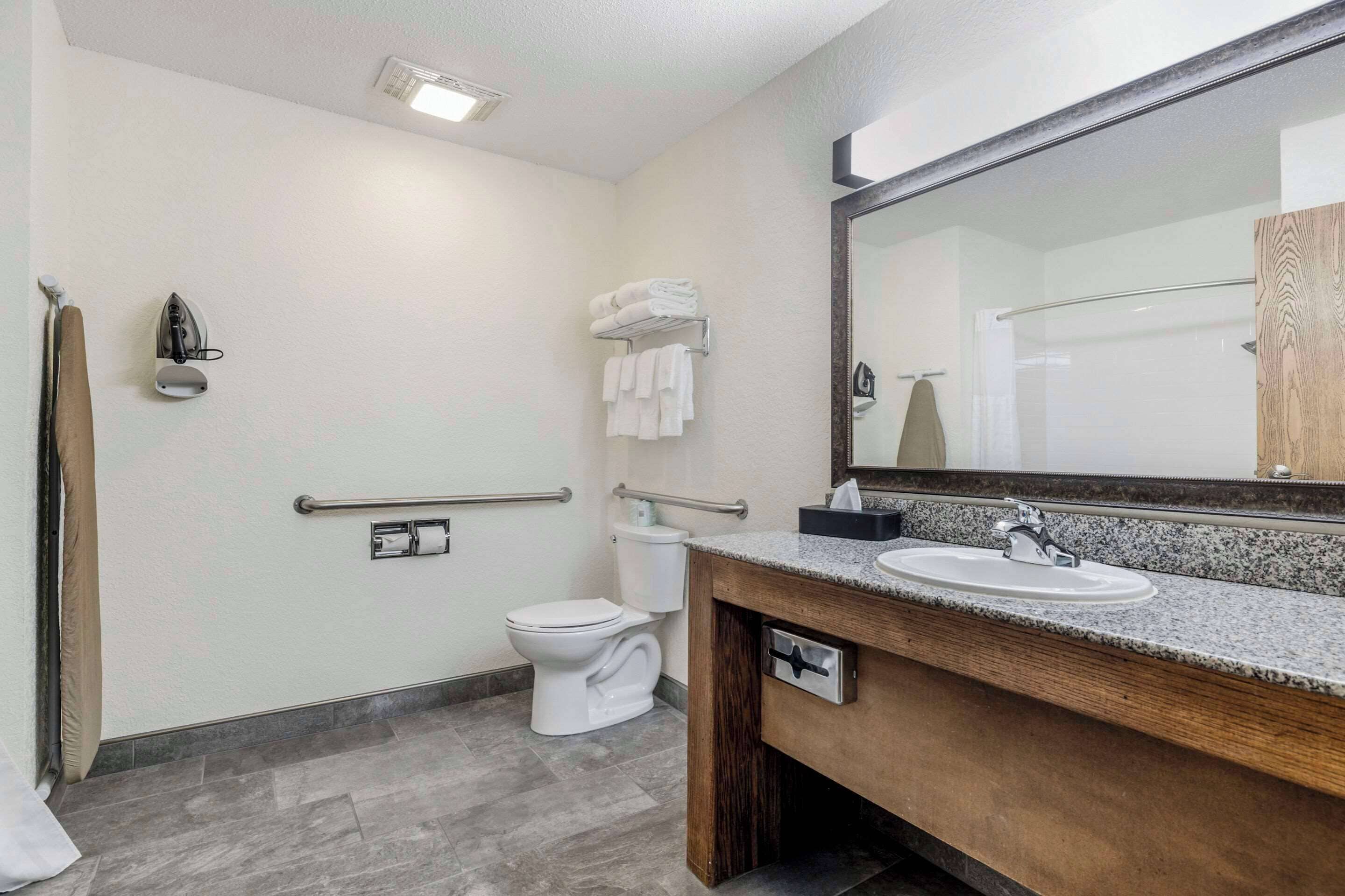A bathroom with a toilet, sink, and mirror.