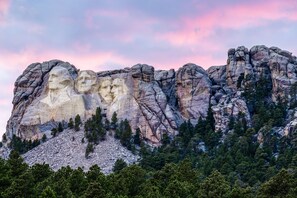 A mountain with carved faces and a forested base. - Comfort Inn & Suites Mt. Rushmore (Keystone)