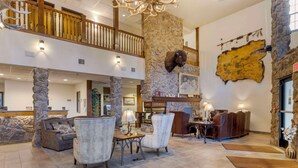 A spacious lobby with a high ceiling, stone pillars, and a wooden balcony. - Comfort Inn & Suites Mt. Rushmore (Keystone)
