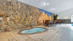 An indoor pool area with stone walls, a mural, and seating. - Comfort Inn & Suites Mt. Rushmore (Keystone)
