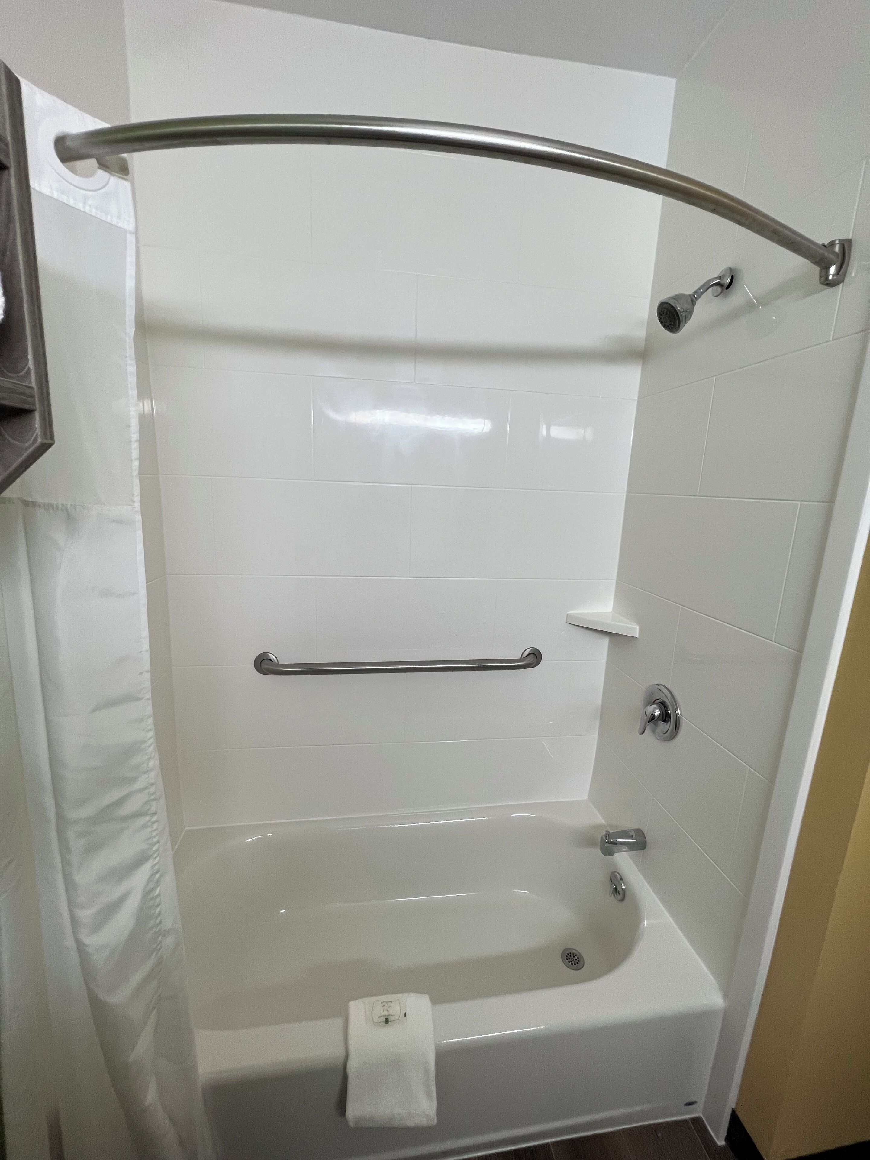 Un baño moderno con ducha acristalada, cabezal de ducha manual, toallero y lavamanos empotrado.