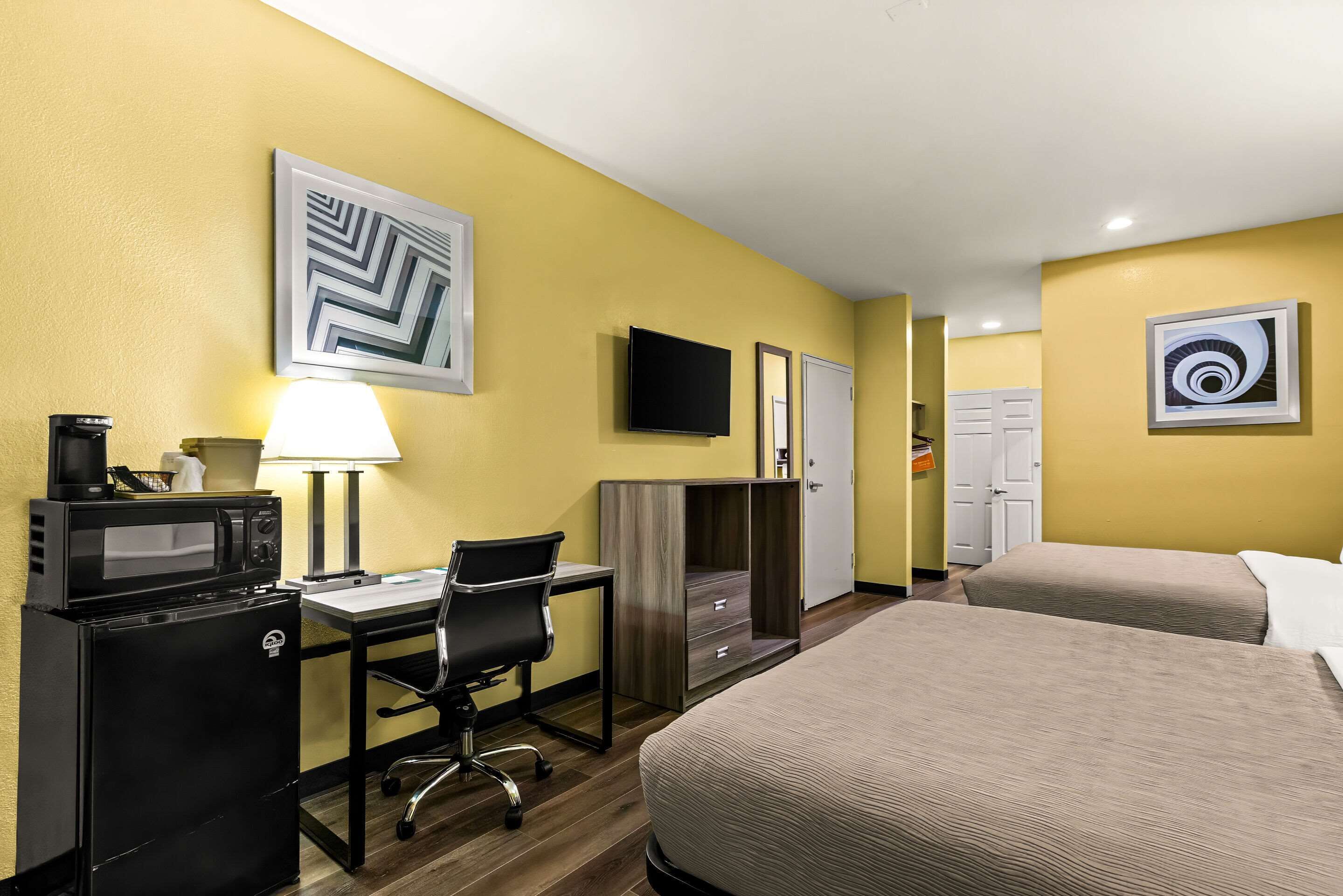 A hotel room with a bed, desk, microwave, and TV.