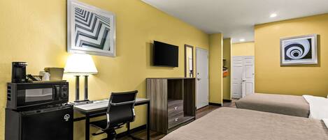 A hotel room with a bed, desk, microwave, and TV.