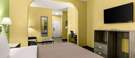 A hotel room with a bed, a desk, a chair, a TV, and a wardrobe.