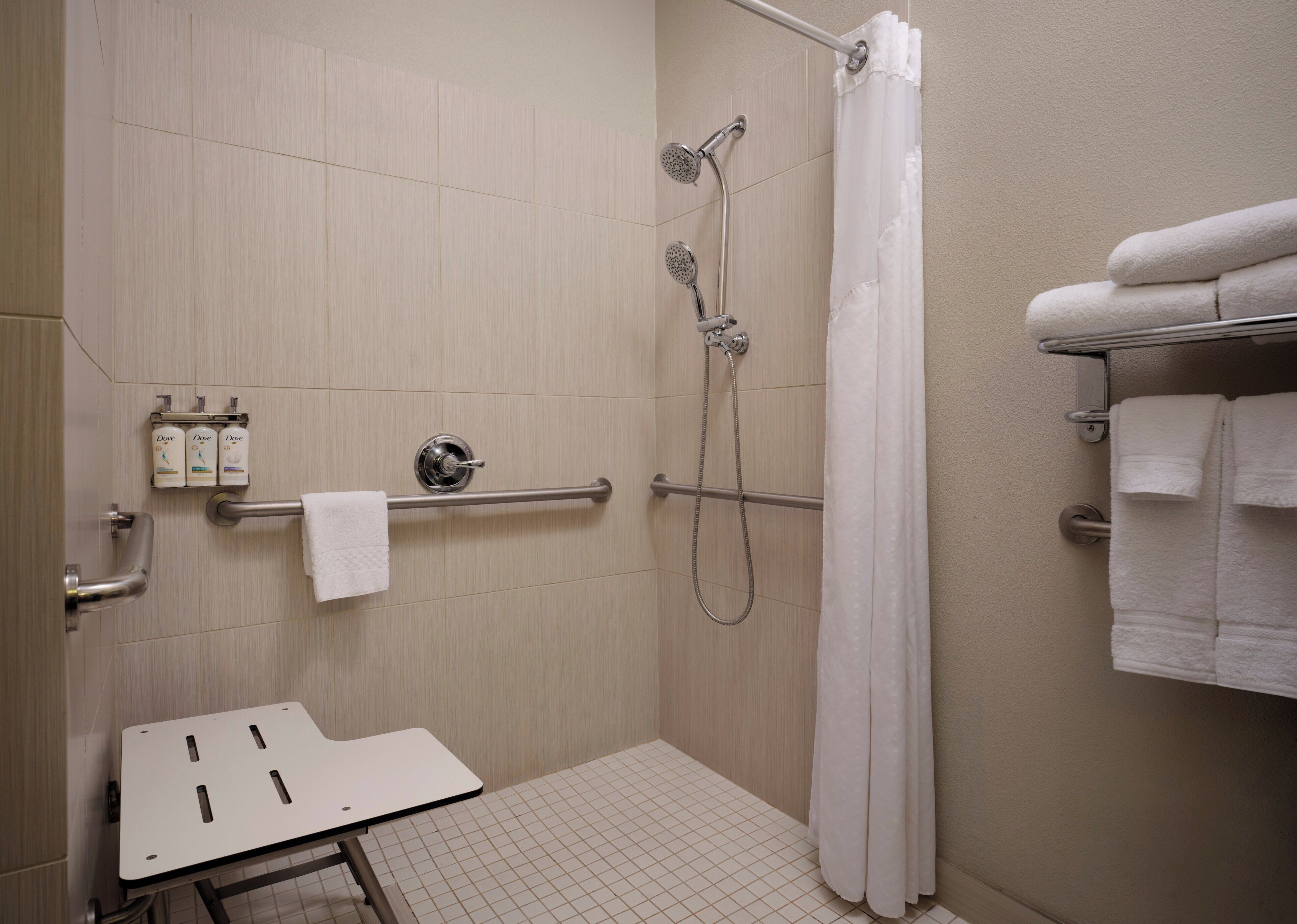 A shower area with a grab bar, a towel rack, and a showerhead.