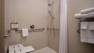 A shower area with a grab bar, a towel rack, and a showerhead.