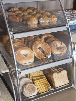 A bakery display case with muffins, bagels, and other baked goods.