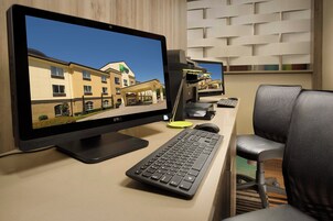 Un mostrador de recepción de hotel con un monitor que muestra el exterior del hotel, un teclado, un ratón y una silla.