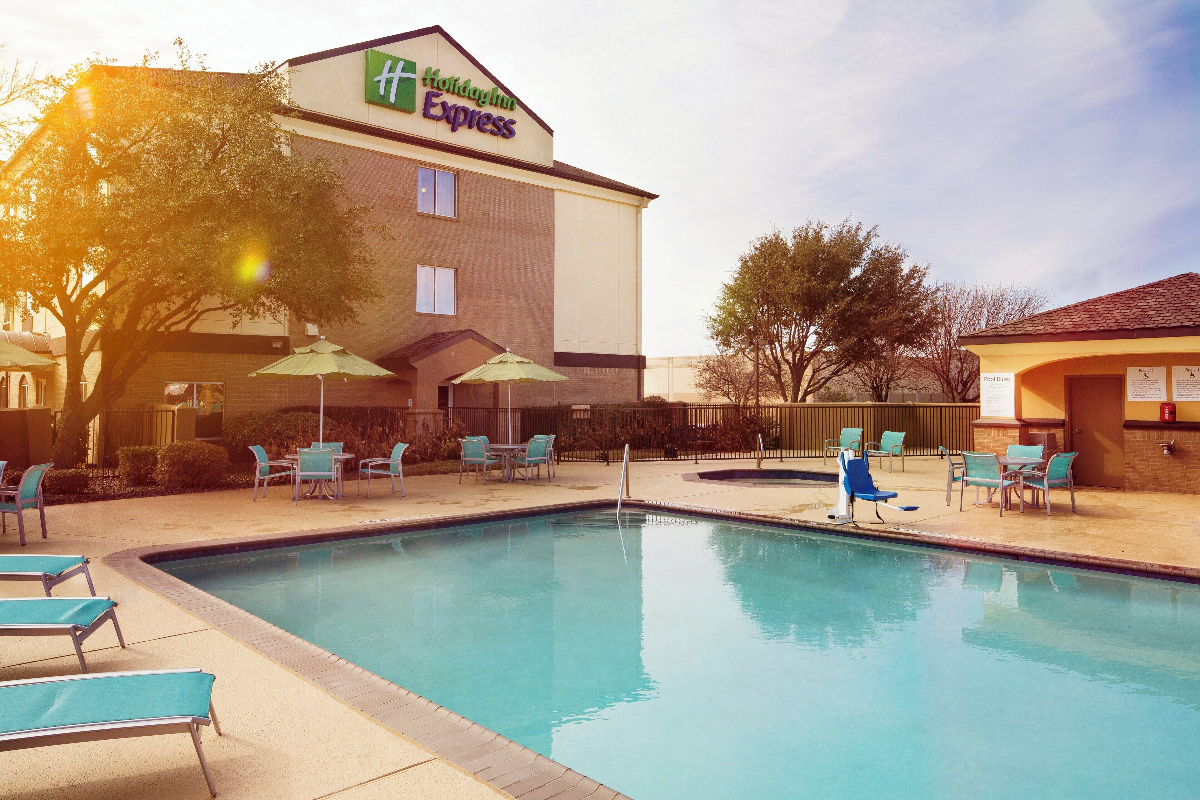 A Holiday Inn Express with a pool area, outdoor seating, and a sign indicating pool rules.