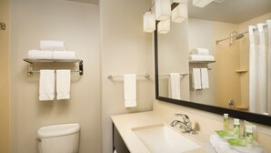 A modern bathroom with a toilet, sink, and a mirror. There are multiple towels on shelves and a shower area. - Holiday Inn Express & Suites DFW - Grapevine by IHG (Grapevine)