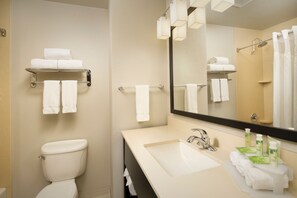 A modern bathroom with a toilet, sink, and a mirror. There are multiple towels on shelves and a shower area. - Holiday Inn Express & Suites DFW - Grapevine by IHG (Grapevine)