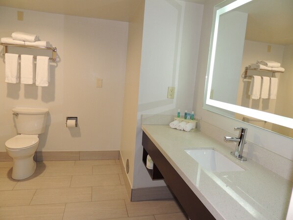 A bathroom with a toilet, a sink, a mirror, and towels.