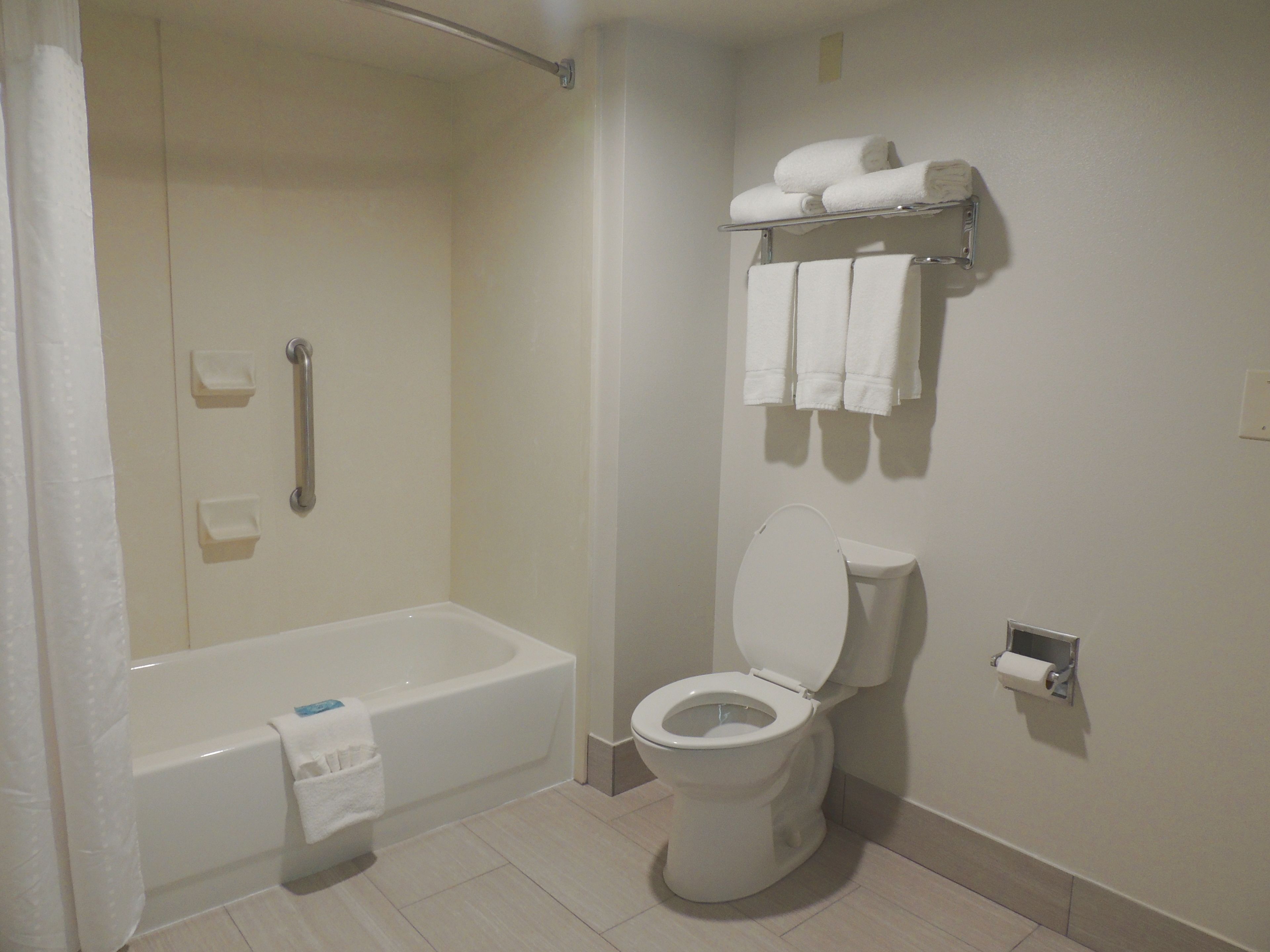 Un baño con bañera, inodoro y un estante con toallas.
