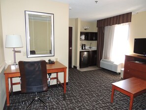 A hotel room with a desk, chair, television, and a kitchenette area. - Holiday Inn Express & Suites Birmingham Trussville by IHG (Birmingham)