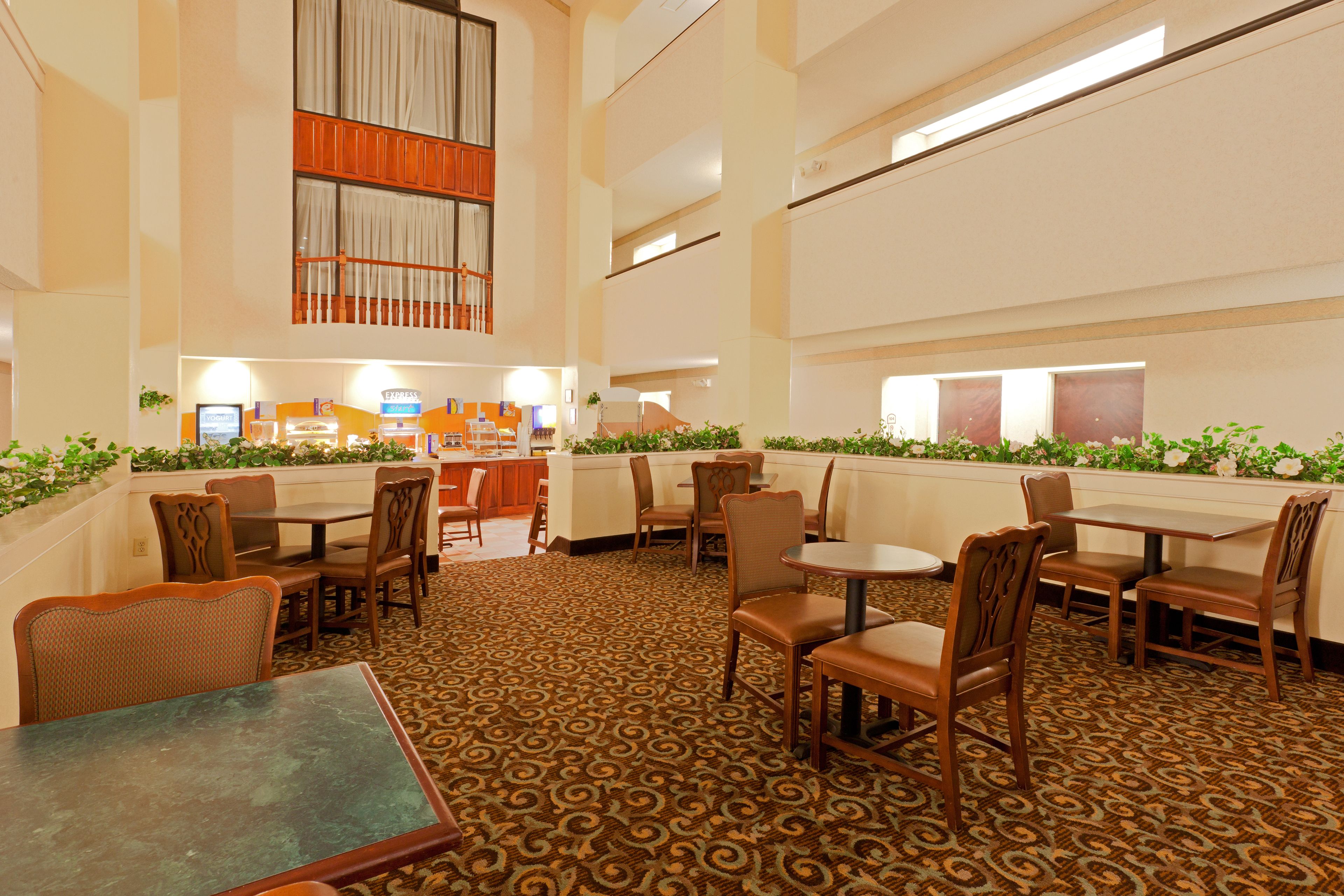 A hotel lobby with multiple seating areas, a reception desk, and a patterned carpet.