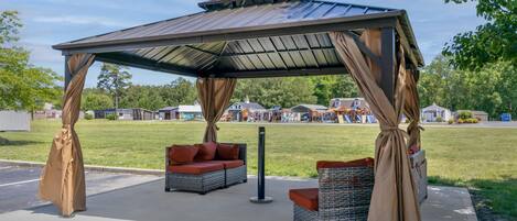 A covered outdoor seating area with wicker furniture and a metal roof.