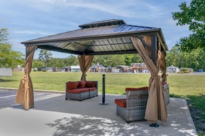 A covered outdoor seating area with wicker furniture and a metal roof.