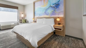 A hotel room with a large bed, bedside lamps, a nightstand, a window with blinds, and a wall-mounted abstract painting. - Best Western Plus Pocomoke City (Pocomoke City)