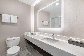 Un bagno moderno con lavandino, specchio e vaso bianco.