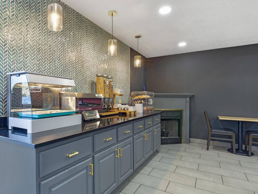 Una cocina moderna con una vitrina empotrada para pasteles, una cafetera y una zona de estar con mesa y sillas.