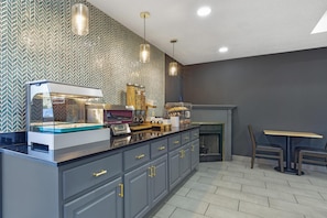 Una cucina moderna con una vetrina integrata per dolci, una macchina per il caffè e un'area salotto con tavolo e sedie.