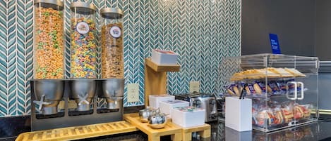 A breakfast bar with cereal dispensers, a coffee machine, and a bread display.