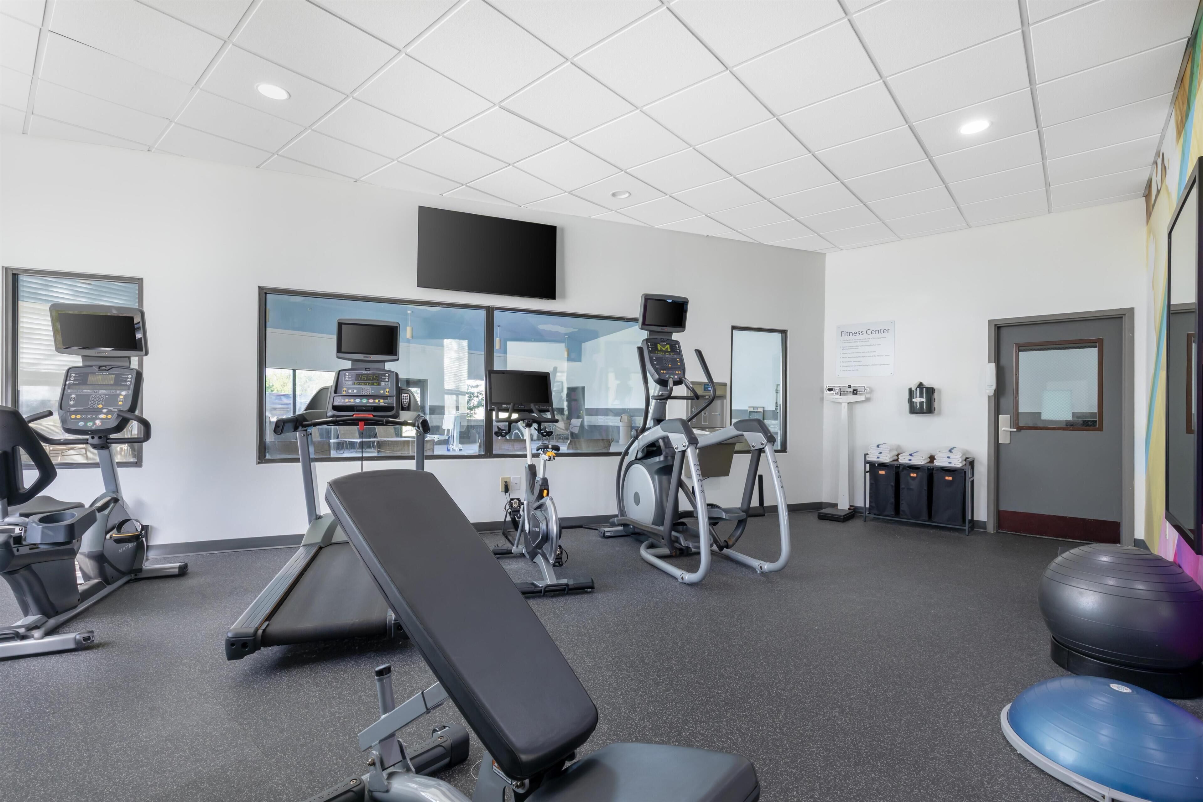 A fitness center with cardio machines, a bench, and a large exercise ball.