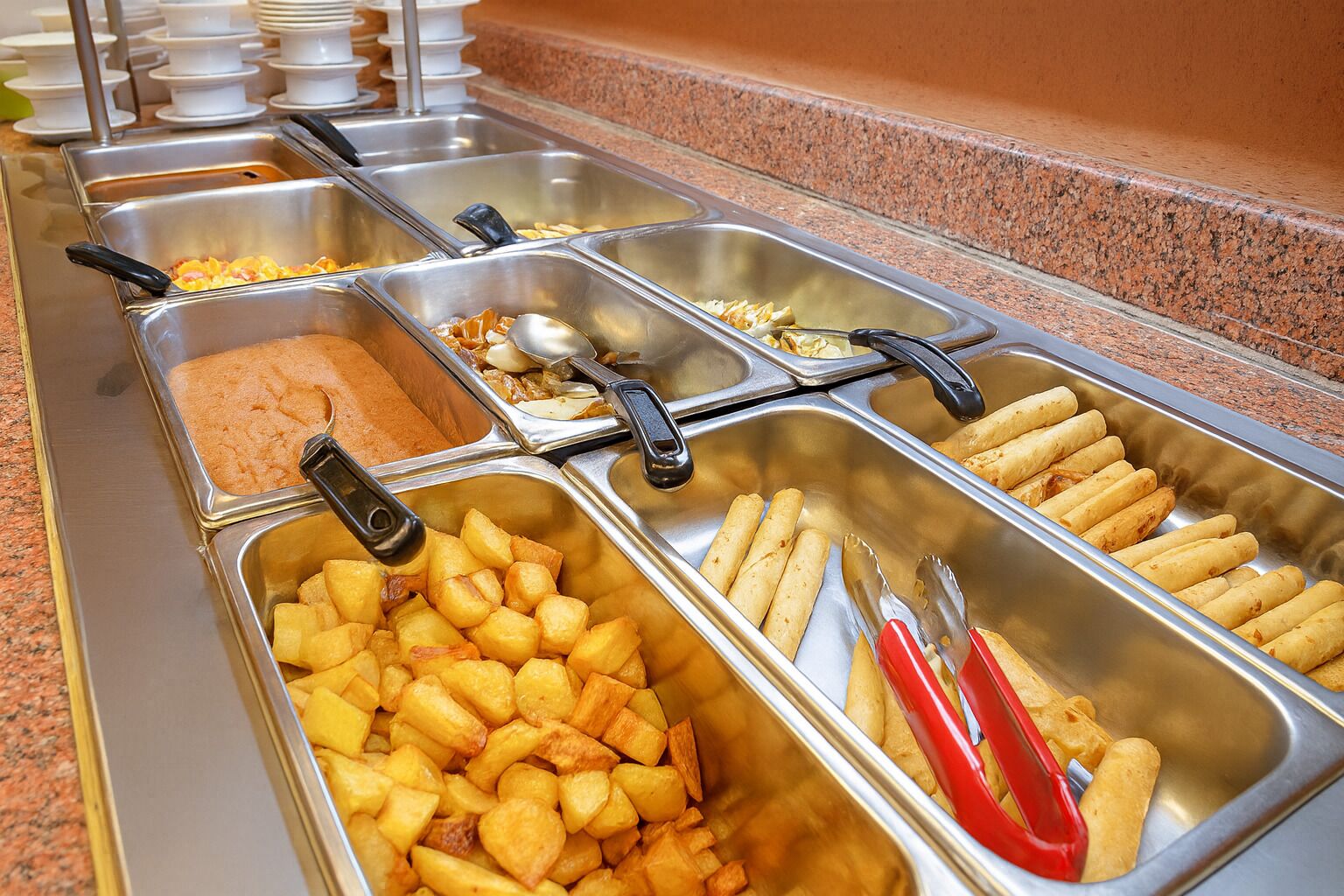 A buffet with various food items including potatoes, tortillas, and a creamy dish.