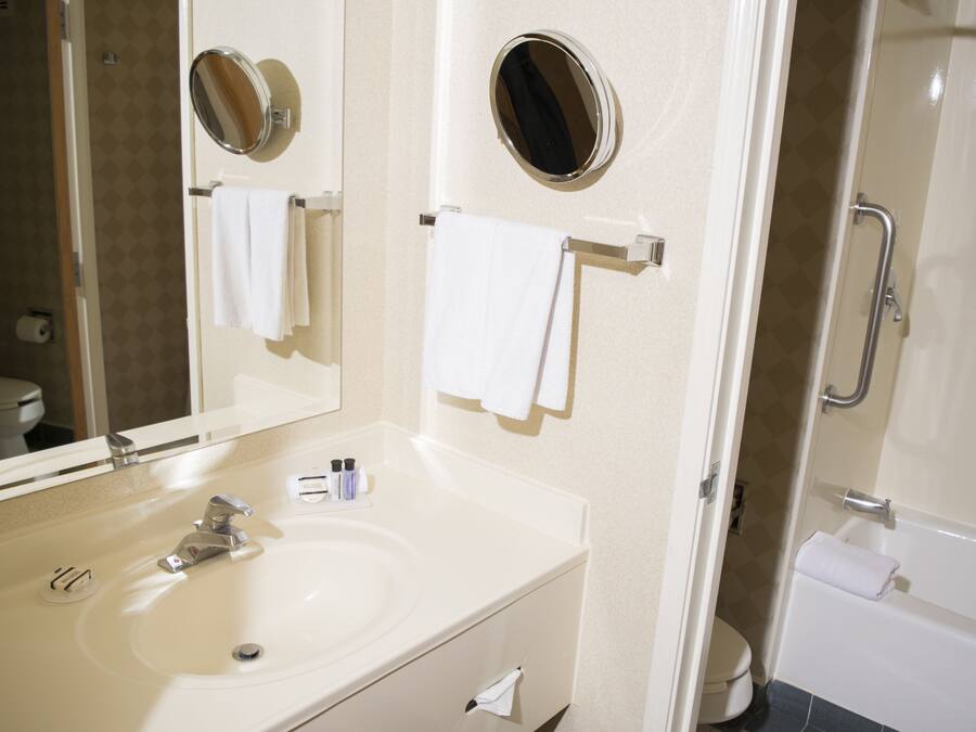 A bathroom with a sink, mirror, and towel rack.