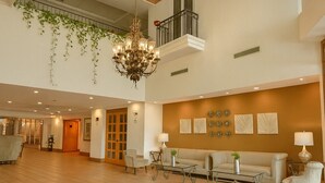 A spacious lobby with a high ceiling, a chandelier, a balcony with plants, and a seating area with a sofa and chairs. - iStay Hotel Ciudad Victoria (Ciudad Victoria)