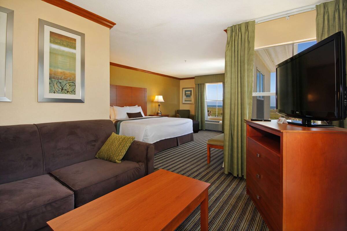 Een hotelkamer met een bed, een slaapbank, een televisie en een bureau.