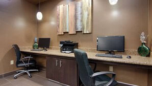 Un comptoir d’accueil équipé de deux écrans d’ordinateur, d’une imprimante et d’un clavier. On y trouve également deux chaises de bureau et un vase contenant des objets décoratifs.