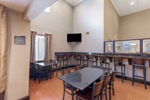 A dining area with a long table and chairs, a television mounted on the wall, and a window with curtains. - Best Western Plus Russellville Hotel & Suites (Russellville)
