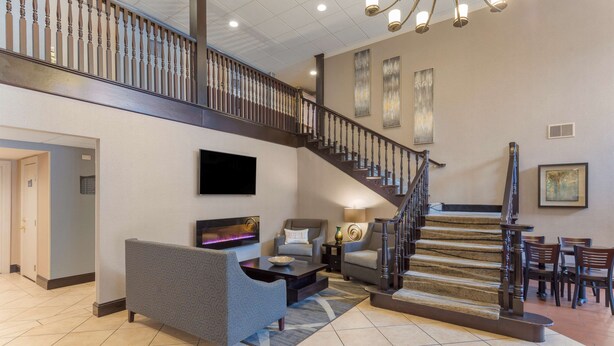 Un vaste espace de vie comprenant un escalier, un téléviseur à écran plat et un coin salon avec une table basse.